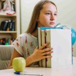 Student holding books during science revision.