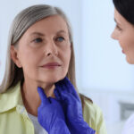 Endocrinologist examining thyroid gland of patient at hospital